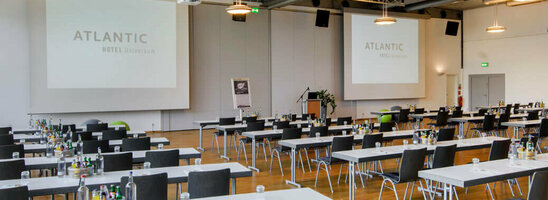 Modern conference room in the ATLANTIC Hotel Universum with tables, chairs and large windows.