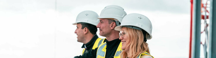 3 Personen stehen lächelnd auf der Baustelle des ATLANTIC Hotel Frankfurts