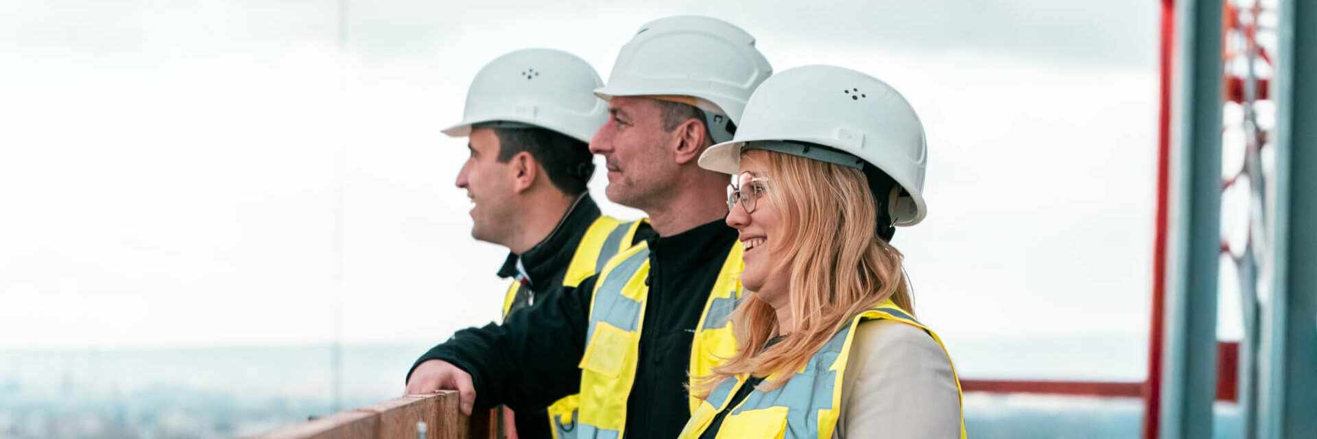 3 Personen stehen lächelnd auf der Baustelle des ATLANTIC Hotel Frankfurts