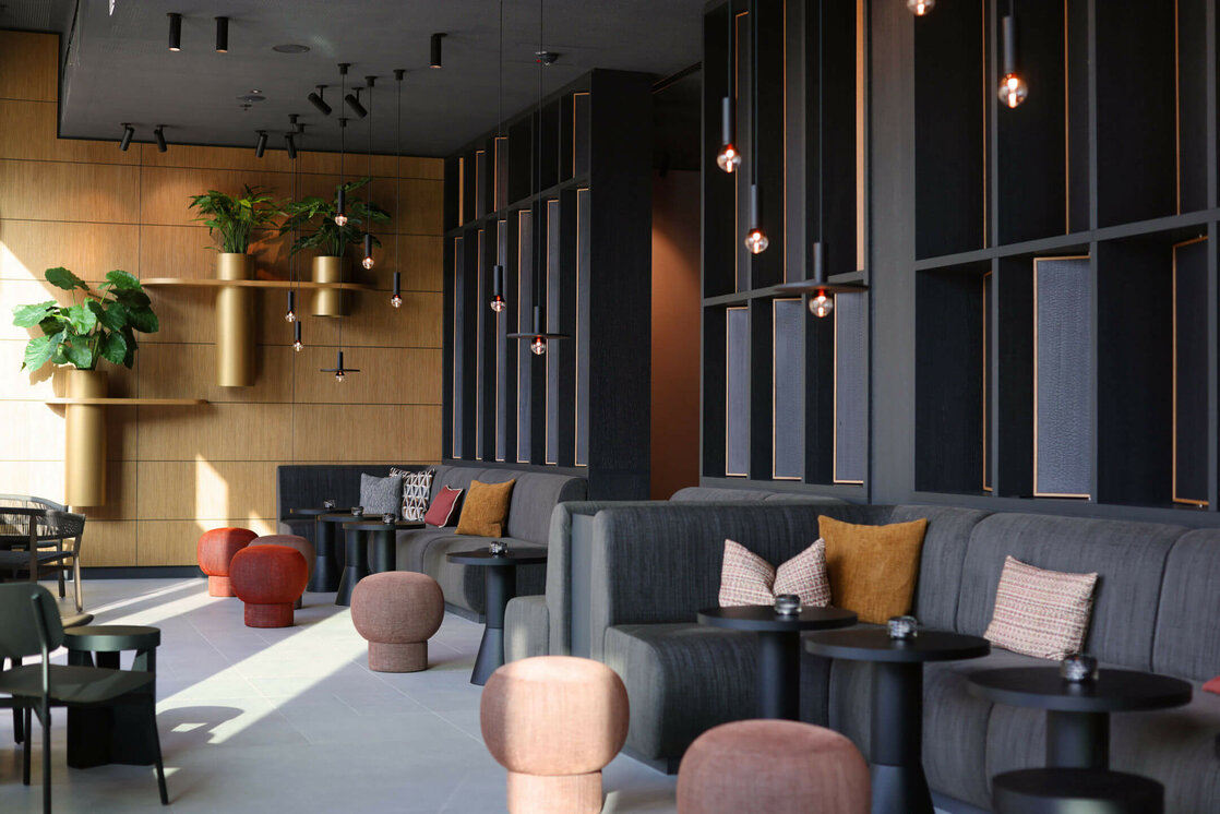 Deli Lounge im ATLANTIC Hotel Heidelberg Moderne Hotel-Lounge mit eleganten Sitzgruppen, Pflanzen und stilvoller Beleuchtung im ATLANTIC Hotel Heidelberg.