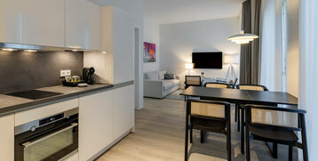 Moderne Suite mit Küche, Esstisch, Sofa und TV im ATLANTIC Grand Hotel Travemünde.