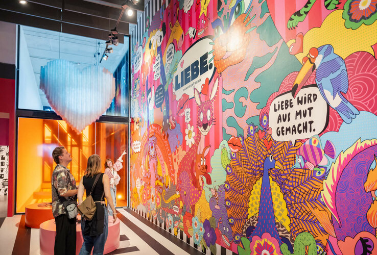 Bunte Wandmalerei im Universum Bremen, zeigt kreative Tiermotive und den Schriftzug "Liebe wird aus Mut gemacht".