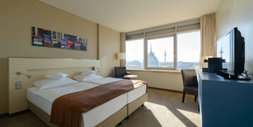 Bright hotel room with double bed, large windows, city view and modern furnishings at the ATLANTIC Hotel Sail City.