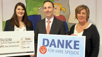 Drei Personen halten einen Scheck und ein Dankesschild für eine Spende im ATLANTIC Hotel Wilhelmshaven.