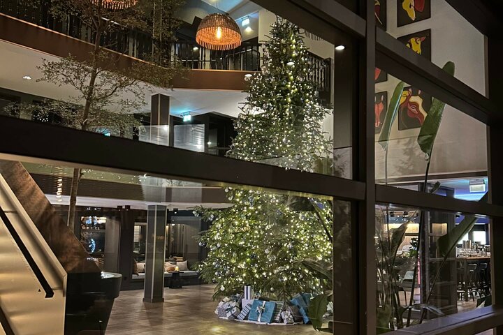 Beleuchteter Weihnachtsbaum in der Lobby des ATLANTIC Hotel Landgut Horn Bremen, umgeben von Geschenken und Pflanzen.