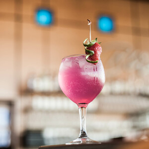 Cocktail in the ATLANTIC Hotel Airport Pink cocktail garnished with strawberry and lime, served at the ATLANTIC Hotel Airport Bremen.