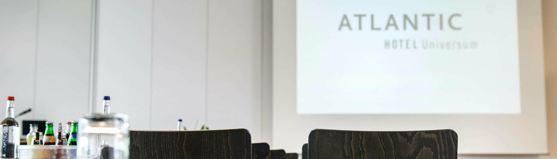 Conference room in the ATLANTIC Hotel Universum with chairs, tables and drinks, view of a projection screen.