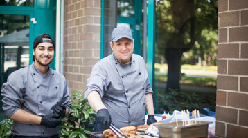 Köche grillen Würstchen und Fleisch vor dem ATLANTIC Hotel Airport Bremen.