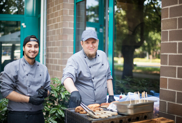 Cooks grill sausages and meat in front of the ATLANTIC Hotel Airport Bremen.