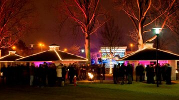 Group of people at a night event at the ATLANTIC Hotel Galopprennbahn, illuminated pavilions and trees in the background.