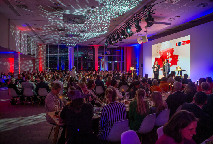 Festlich beleuchteter Veranstaltungsraum im ATLANTIC Hotel Sail City mit Gästen und einer Bühne im Hintergrund.