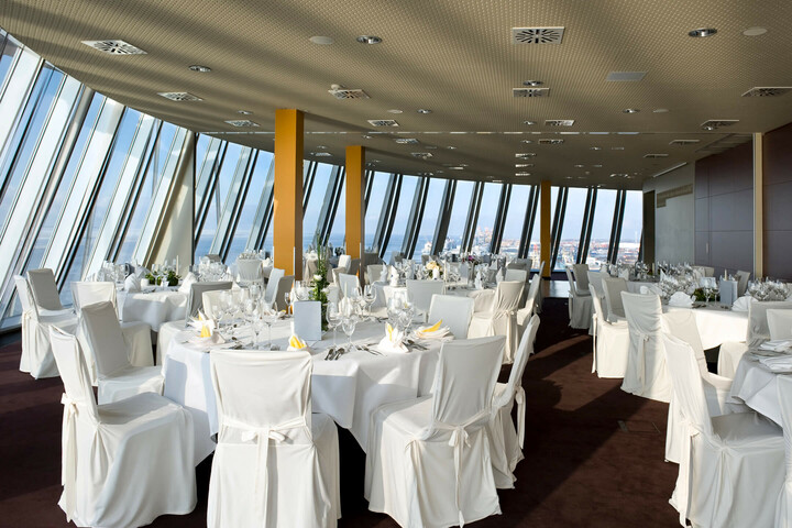 Marry over the roofs of Bremerhaven in the Captain´s Lounge of the ATLANTIC Hotel Sail City Bright event room in the ATLANTIC Hotel Sail City with white-clothed tables and a panoramic view of Bremerhaven.