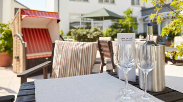 Terrace of the ATLANTIC Hotel Vegesack Terrace of the ATLANTIC Hotel Vegesack with beach chair, laid table and bottle of wine outside.