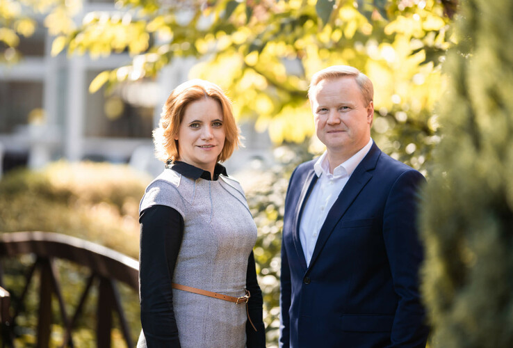 Ein Mann und eine Frau stehen lächelnd im Garten des ATLANTIC Hotel Landgut Horn Bremen.