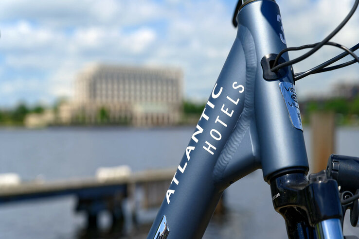 Fahrrad mit "Atlantic Hotels"-Aufschrift vor unscharfem Wasser- und Gebäudehintergrund.