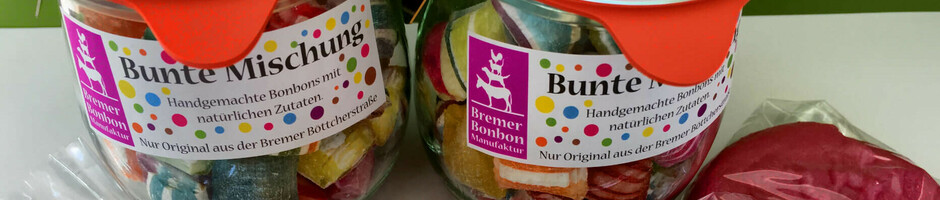 Colorful sweets in jars and large lollipops in orange, green and red, wrapped in transparent foil.