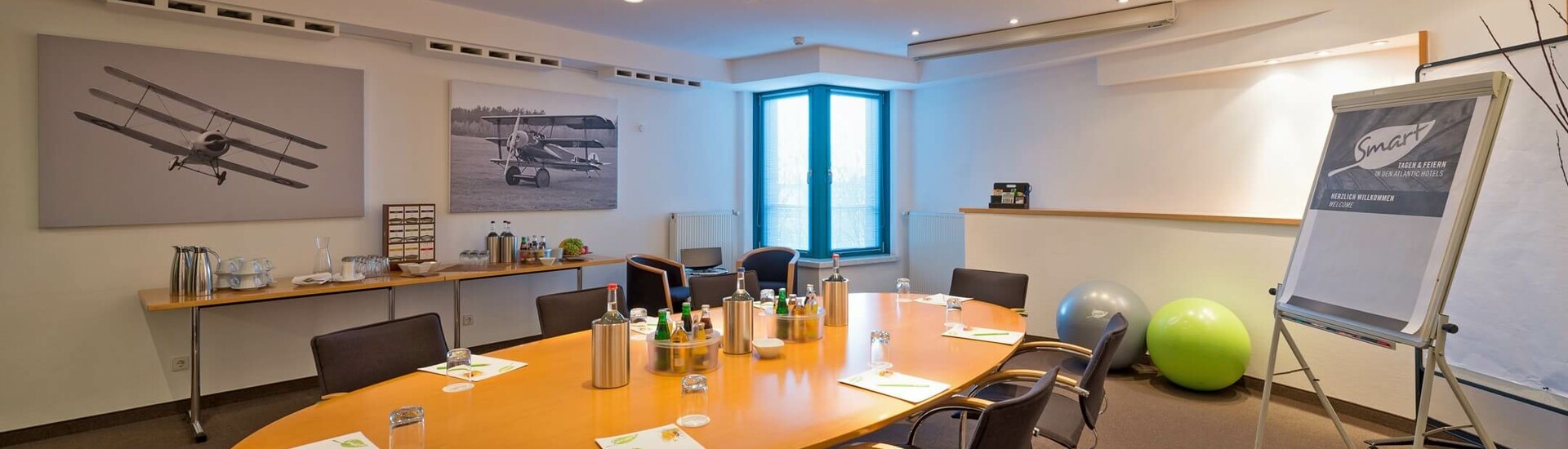 Function room Fokker in the ATLANTIC Hotel Airport Bremen Modern conference room with oval table, chairs, flipchart and murals at the ATLANTIC Hotel Airport Bremen.
