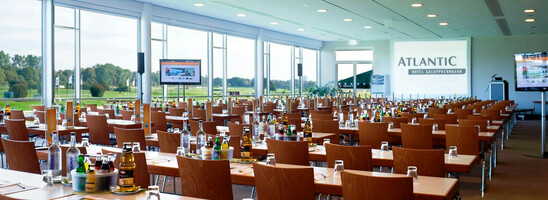Modern conference room at the ATLANTIC Hotel Galopprennbahn Bremen with tables, chairs and a view of the racecourse.