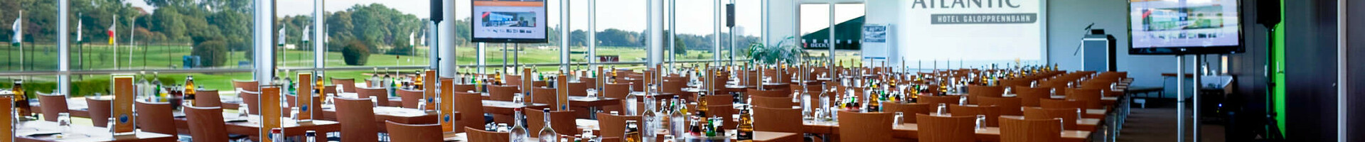 Moderner Konferenzraum im ATLANTIC Hotel Galopprennbahn Bremen mit Tischen, Stühlen und Blick auf die Rennbahn.