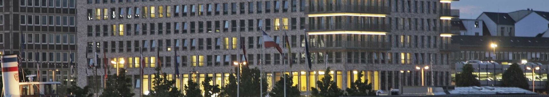Modernes Hotelgebäude am Wasser bei Abenddämmerung, beleuchtet mit reflektierendem Licht im Fluss.