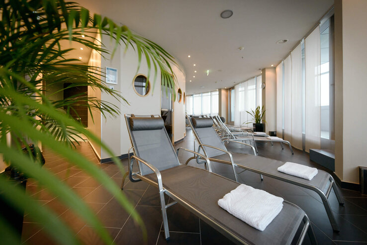 Relaxation area in the ATLANTIC Hotel Sail City Bright relaxation room in the ATLANTIC Hotel with loungers and towels, surrounded by plants.