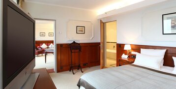Bedroom with a bed and flatscreen TC in the Cutty Sark Suite of the ATLANTIC Hotel Wilhelmshaven 