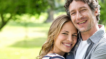 Lächelndes Paar umarmt sich im grünen Park vor dem ATLANTIC Hotel Universum in Bremen.