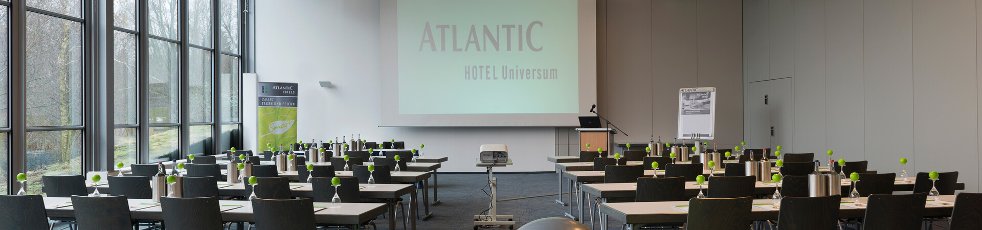 Modern conference room in the ATLANTIC Hotel Universum with tables, chairs, exercise balls and a large screen.