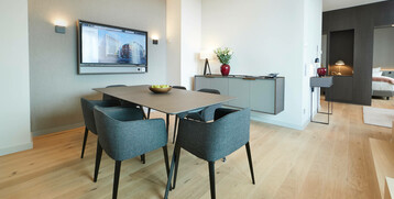 Modern conference room with table, four chairs, wall screen and stylish decoration at the ATLANTIC Grand Hotel Bremen.