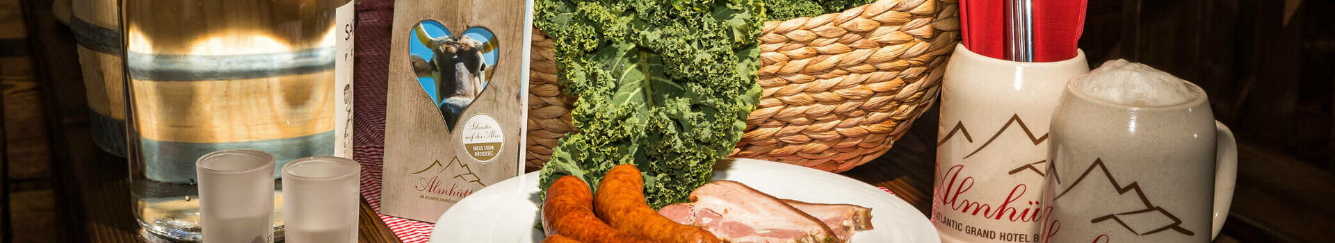 Grünkohl-Menü in der Almhütte am ATLANTIC Grand Hotel Bremen Rustikaler Tisch mit Grünkohl, Würstchen, Speisekarte und Bierkrug im ATLANTIC Grand Hotel Bremen.