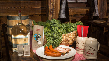 Rustikaler Tisch mit Grünkohl, Würstchen, Speisekarte und Bierkrug im ATLANTIC Grand Hotel Bremen.