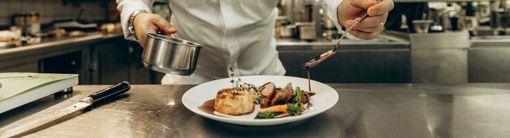 Ein Koch richtet Essen in einer professionellen Küche an 