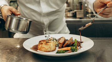 Ein Koch richtet Essen in einer professionellen Küche an 