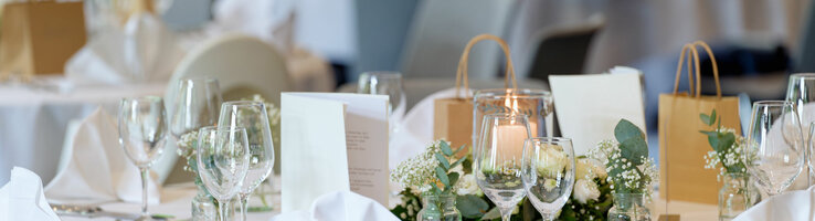 Elegant, festively laid table with white tablecloths, flower arrangements and candles at the ATLANTIC Hotel Landgut Horn Bremen.