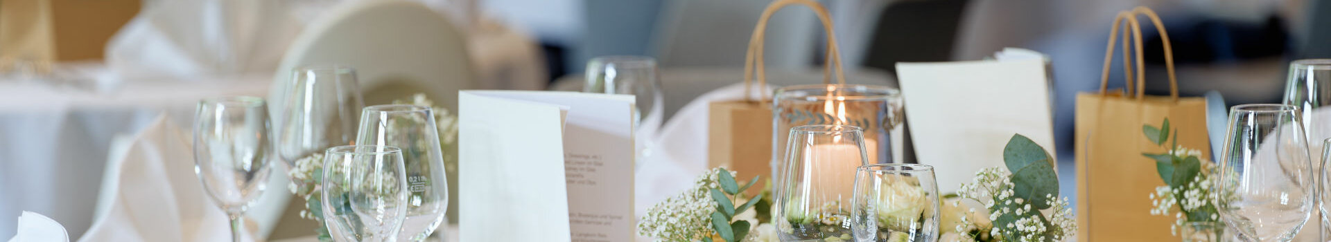 Elegant, festively laid table with white tablecloths, flower arrangements and candles at the ATLANTIC Hotel Landgut Horn Bremen.
