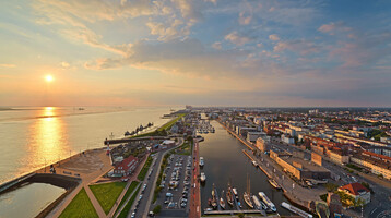 Aussicht auf den neuen Hafen in Bremerhaven Blick auf Bremerhaven vom ATLANTIC Hotel Sail City bei Sonnenuntergang, mit Hafen, Fluss und Stadtpanorama.