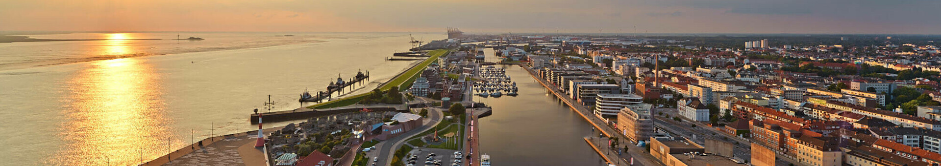 Blick auf Bremerhaven vom ATLANTIC Hotel Sail City bei Sonnenuntergang, mit Hafen, Fluss und Stadtpanorama.