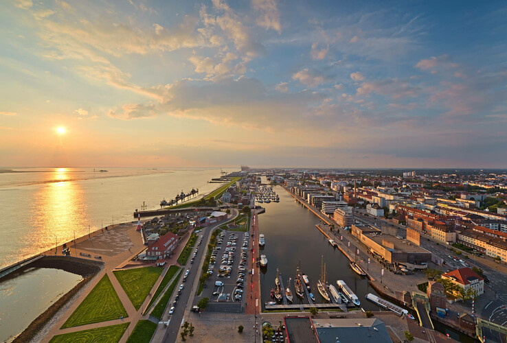 Blick auf Bremerhaven vom ATLANTIC Hotel Sail City bei Sonnenuntergang, mit Hafen, Fluss und Stadtpanorama.