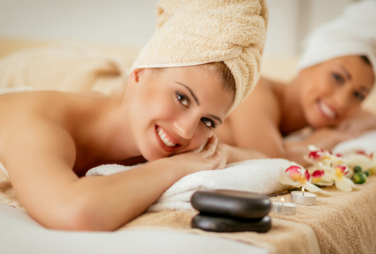 Two women relax during a spa treatment with towels, candles and flowers at the ATLANTIC Grand Hotel Travemünde.