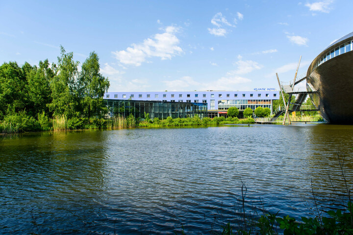 ATLANTIC Hotel Universum in Bremen ATLANTIC Hotel Universum with a view of a calm lake and green surroundings under a sunny sky.