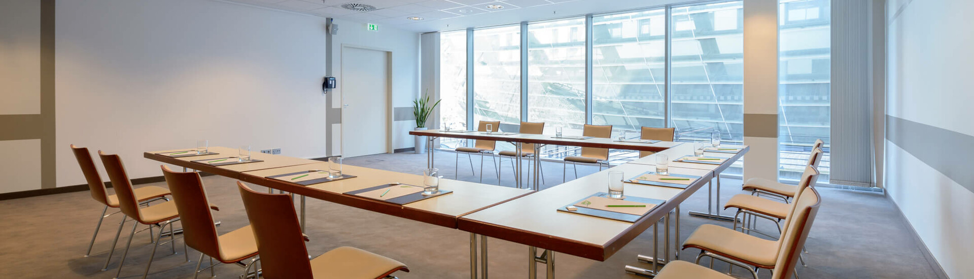 Tagungsraum Conference Saal 4 in U-Form im ATLANTIC Hotel Sail City Heller Konferenzraum im ATLANTIC Hotel Sail City, Bremerhaven, mit U-förmiger Tischanordnung und modernen Stühlen.