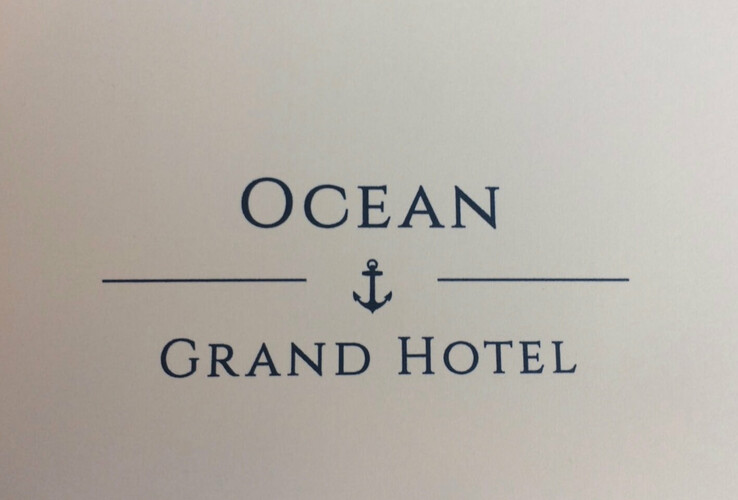 Text "Ocean Grand Hotel" mit einem Anker in der Mitte auf hellem Hintergrund.