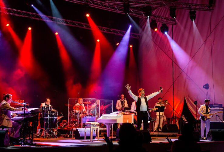 Live-Band spielt auf Bühne mit bunten Lichtern im ATLANTIC Grand Hotel Travemünde. Sänger hebt Arme.