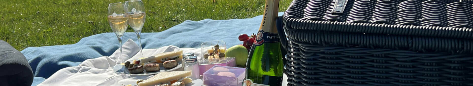 Picnic on the grass with blanket, champagne, snacks and basket in front of the ATLANTIC Grand Hotel Travemünde.