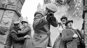 Scenic murder mystery dinner: people in period dress, dramatic scene with smoke, ATLANTIC Grand Hotel Travemünde.
