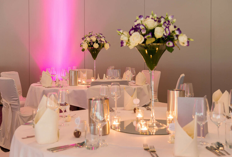 Elegante, festlich gedeckte Tische mit Blumenarrangements und Kerzen im ATLANTIC Hotel Universum Bremen.