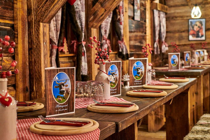 Feast & celebrate in an alpine atmosphere Comfortably laid wooden table in a rustic ambience with menu cards and red accents at the ATLANTIC Grand Hotel Bremen.