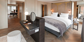 Modern hotel room with large bed, desk, seating area and stylish decoration at the ATLANTIC Grand Hotel Bremen.