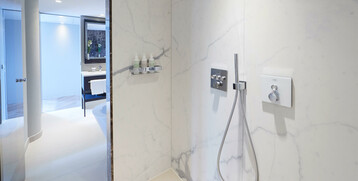 Modern hotel bathroom with rain shower, marble walls and washbasin at the ATLANTIC Grand Hotel Bremen.