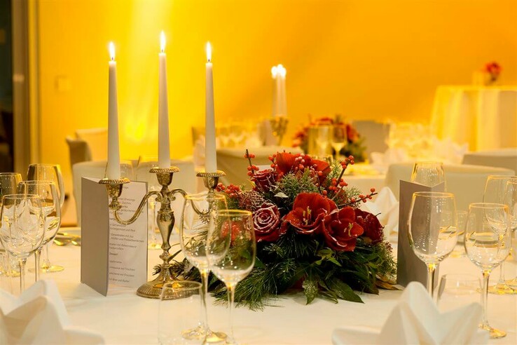 Festlich gedeckter Tisch mit Kerzenleuchter und Blumengesteck im ATLANTIC Hotel Galopprennbahn Bremen.